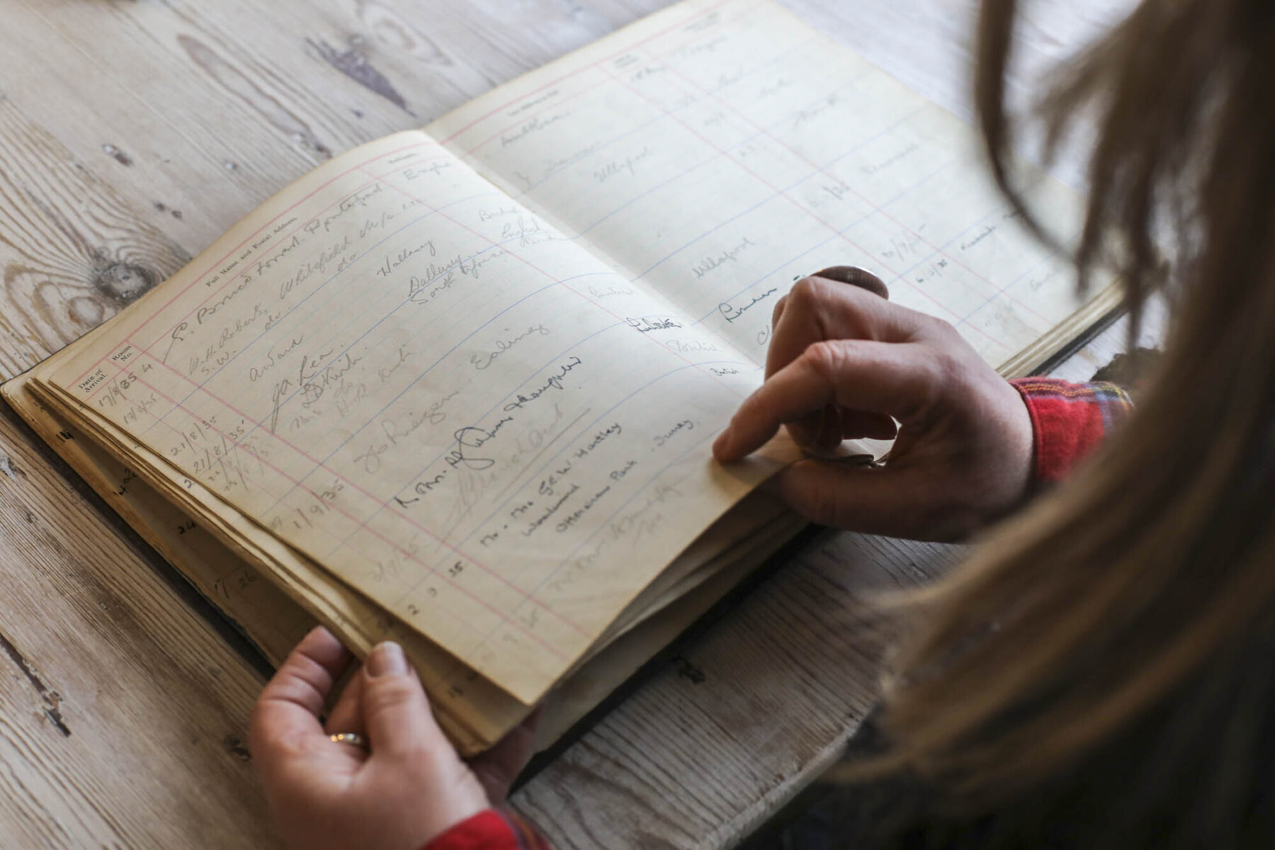 Flicking through Kylesku visitors book from 1950s. Book lying on wooden table.