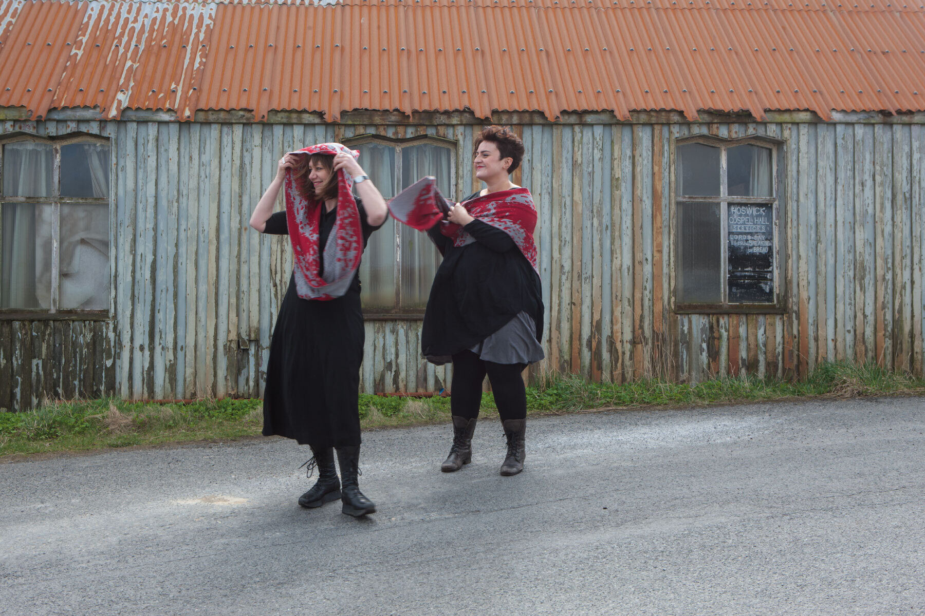 Gail and model in front of wood and tin building in Hoswick, Shetland.