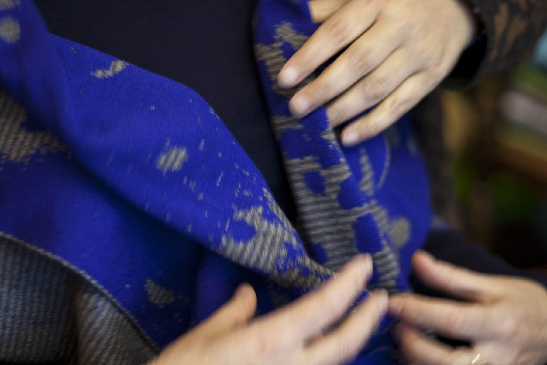 Hands touching and arranging a blue Nielanell Marlet wrap.