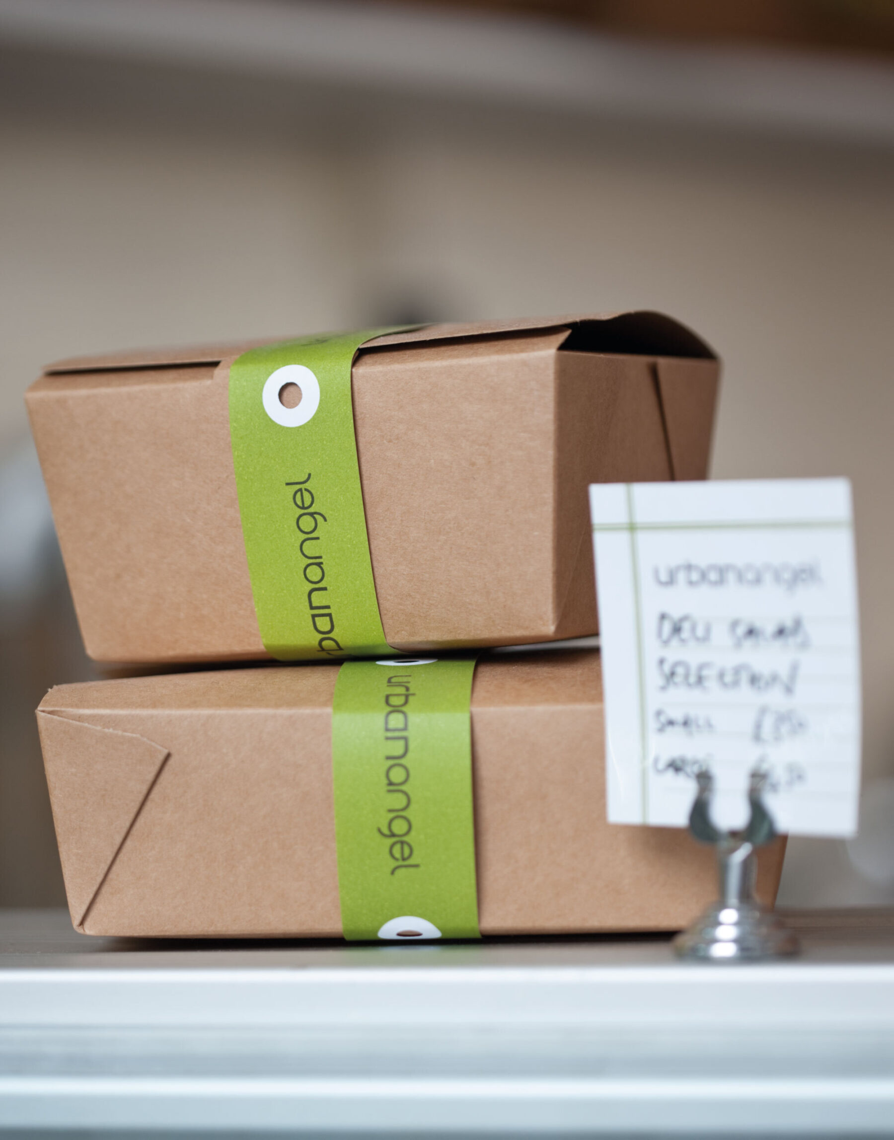 Kraft take-away boxes with green Urbanangel paper ribbon wraps.